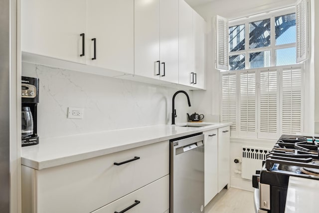 kitchen with dishwasher, radiator, a sink, decorative backsplash, and light countertops