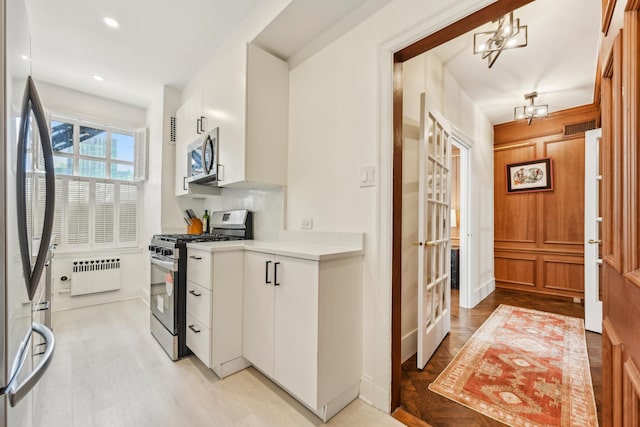 kitchen with radiator, visible vents, white cabinetry, light countertops, and appliances with stainless steel finishes