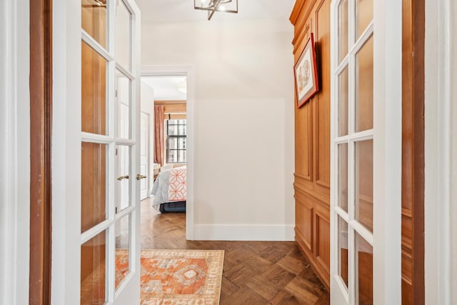hall with an inviting chandelier, french doors, and baseboards