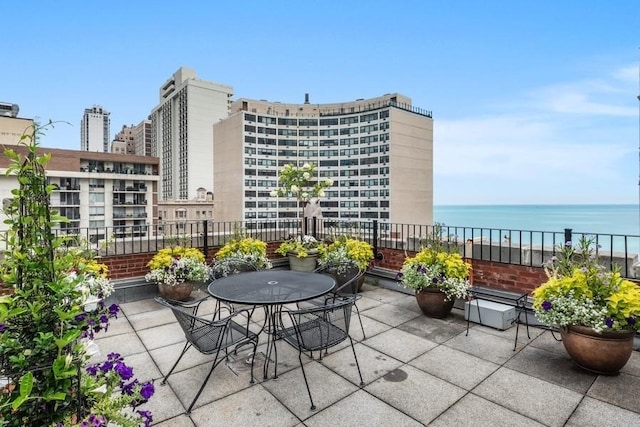 balcony with a patio area, a water view, and outdoor dining space