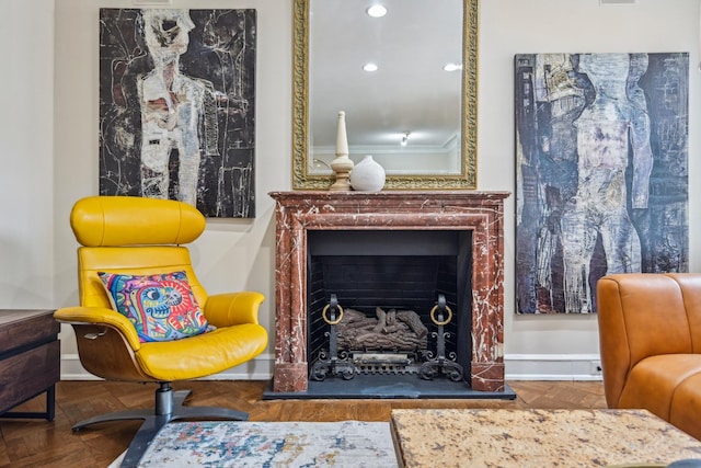 living area with crown molding, a fireplace with raised hearth, and recessed lighting