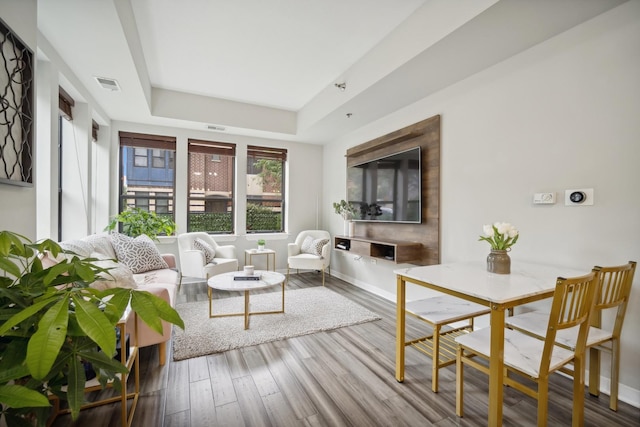living room featuring visible vents, a raised ceiling, and wood finished floors
