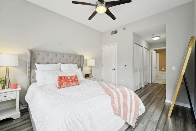 bedroom featuring a ceiling fan, visible vents, wood finished floors, baseboards, and connected bathroom