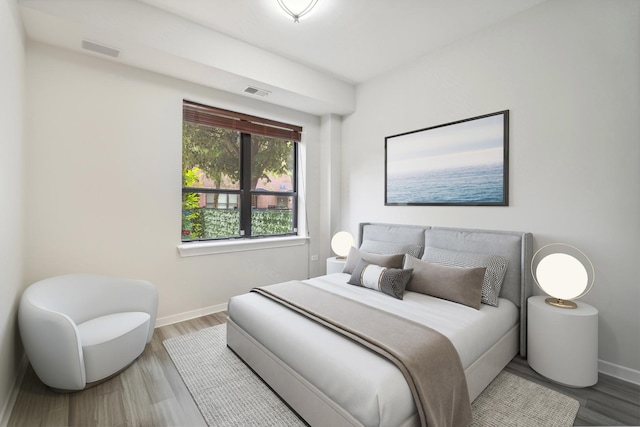 bedroom with baseboards, visible vents, and wood finished floors
