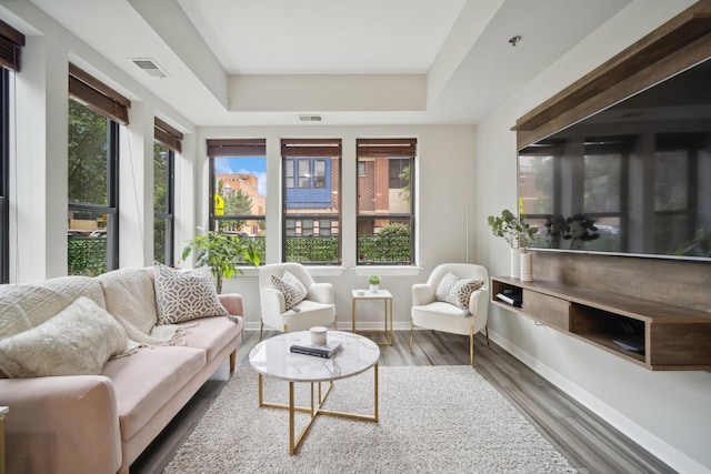 interior space featuring visible vents, baseboards, a raised ceiling, and wood finished floors