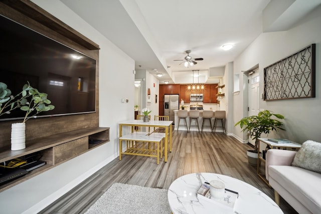 living room featuring baseboards, a ceiling fan, and wood finished floors