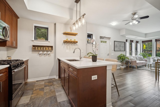 kitchen featuring a breakfast bar, a sink, light countertops, stainless steel appliances, and baseboards