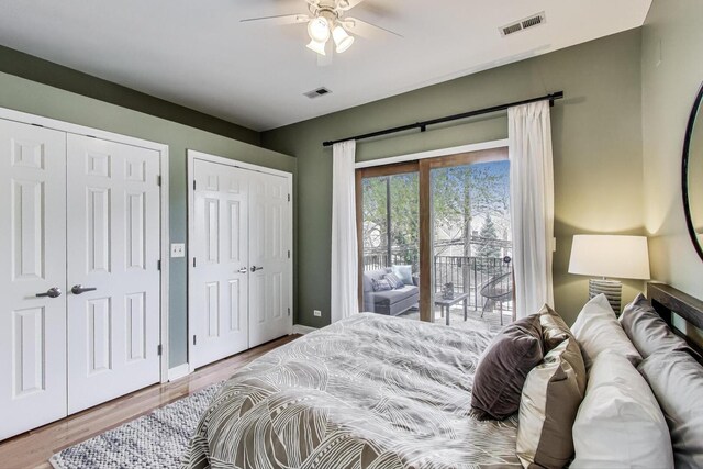 bedroom with multiple closets, visible vents, access to exterior, and wood finished floors
