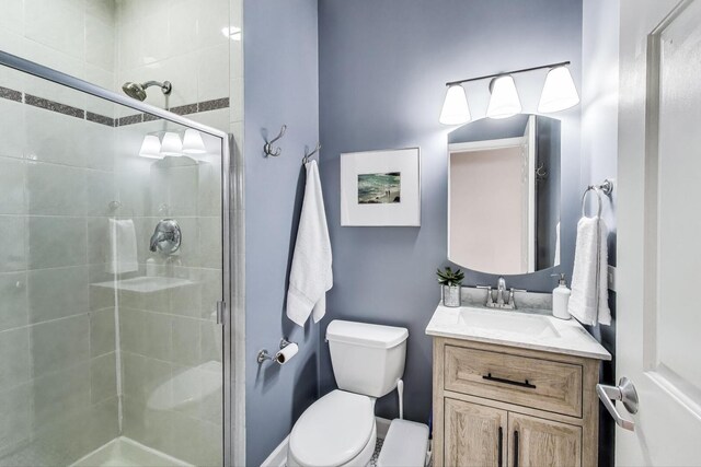 bathroom featuring vanity, a stall shower, and toilet