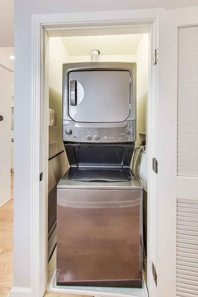 laundry area featuring stacked washer and dryer and wood finished floors