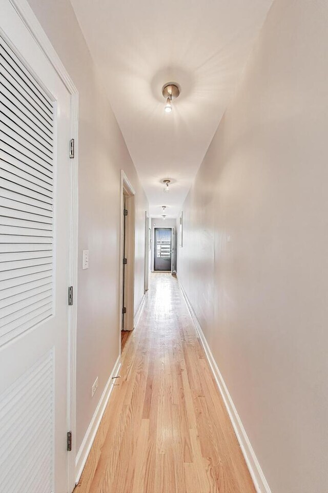 corridor with baseboards and light wood-type flooring