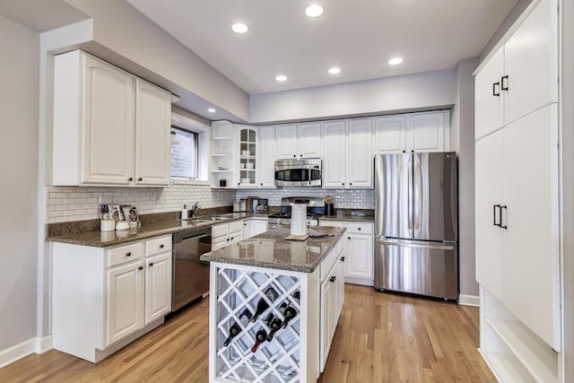 kitchen featuring open shelves, light wood-style flooring, appliances with stainless steel finishes, and dark stone countertops