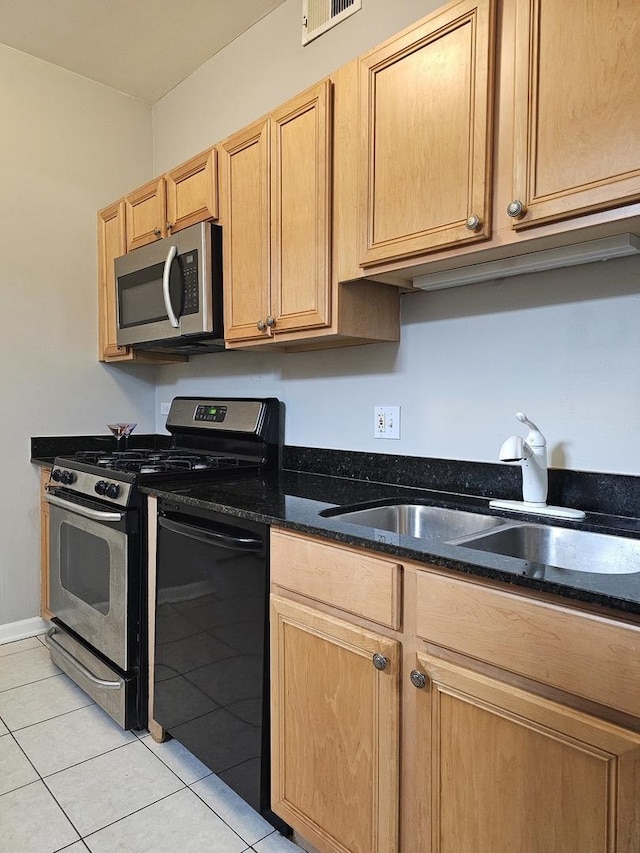 kitchen with stainless steel appliances, a sink, dark stone countertops, visible vents, and light tile patterned floors