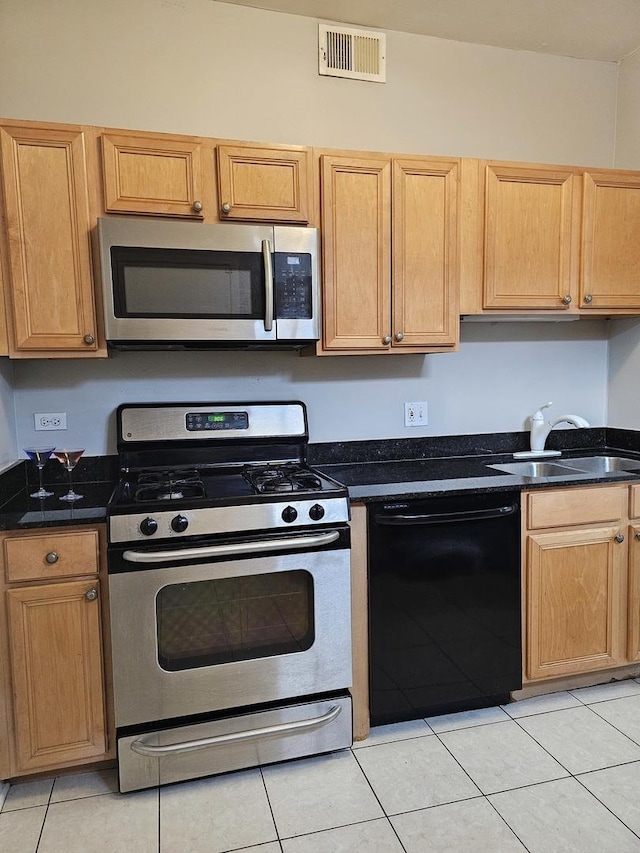 kitchen featuring dark stone countertops, visible vents, light tile patterned floors, a sink, and appliances with stainless steel finishes