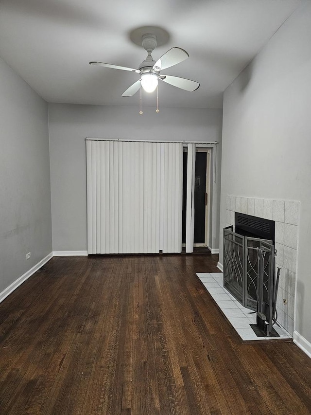 unfurnished living room with ceiling fan, baseboards, wood finished floors, and a tiled fireplace