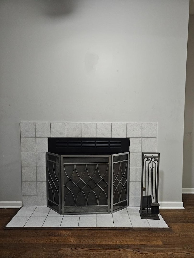 room details featuring baseboards, wood finished floors, and a fireplace