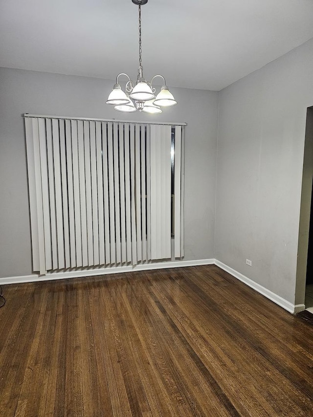 unfurnished room featuring dark wood-type flooring, baseboards, and a notable chandelier
