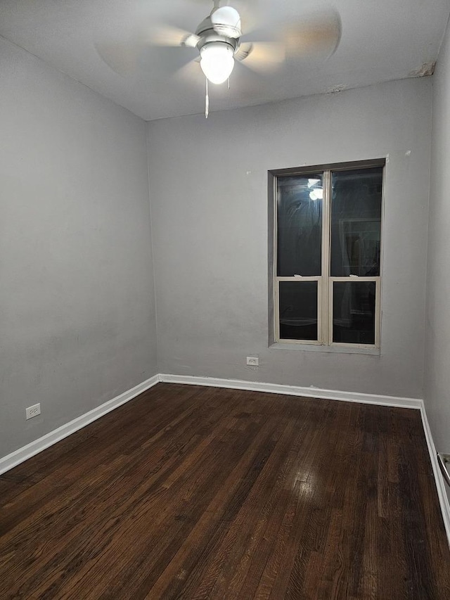 spare room featuring ceiling fan, baseboards, and dark wood-style floors