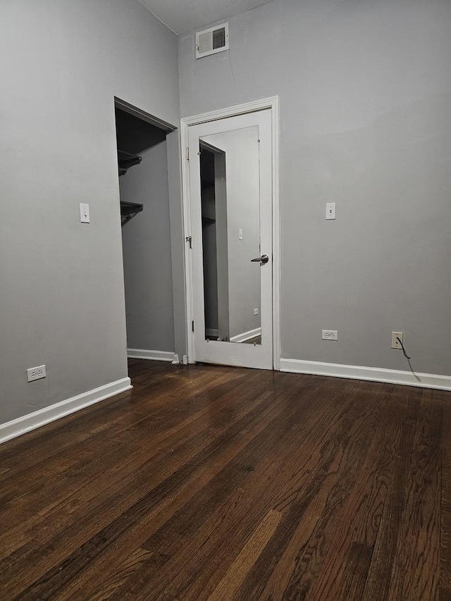 empty room featuring baseboards, wood finished floors, and visible vents