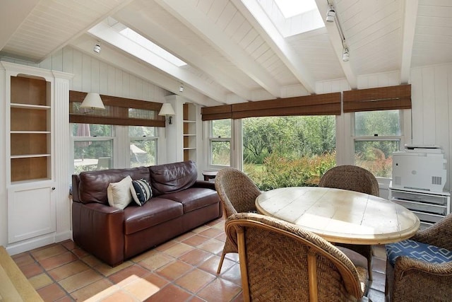 sunroom / solarium featuring a skylight, rail lighting, and beamed ceiling