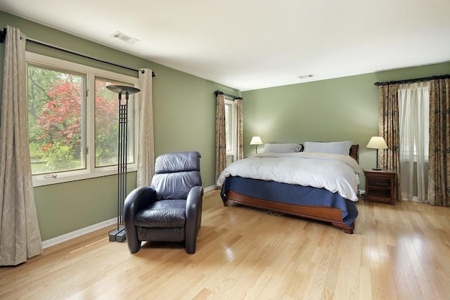bedroom featuring baseboards, wood finished floors, and visible vents