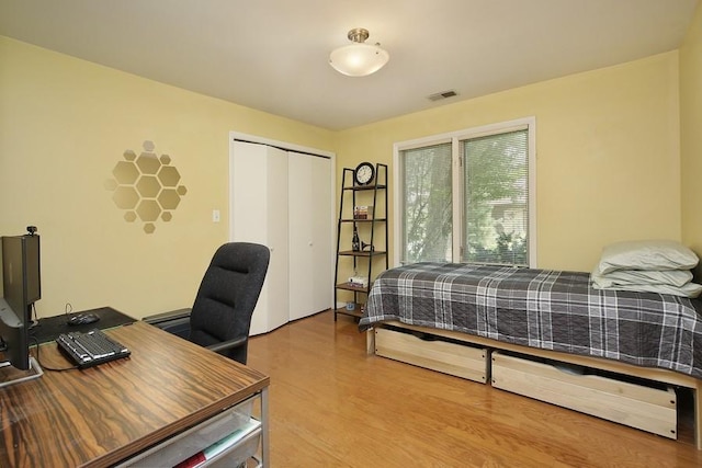 bedroom with visible vents, wood finished floors, and a closet