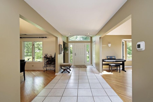 entrance foyer featuring vaulted ceiling, baseboards, and light wood-style floors