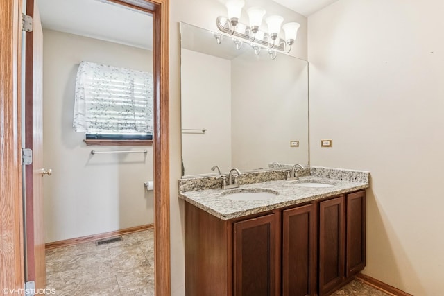 bathroom with a sink, baseboards, double vanity, and visible vents