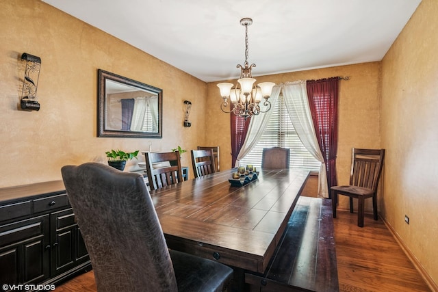dining area with a textured wall, an inviting chandelier, and wood finished floors