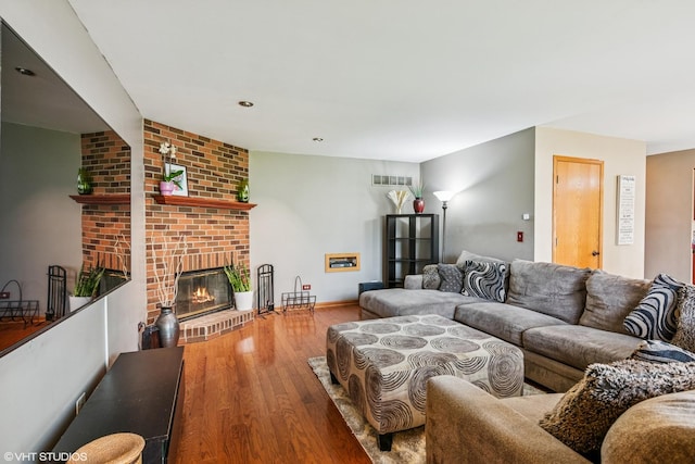 living room with visible vents, baseboards, wood finished floors, and a fireplace