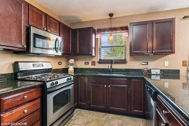 kitchen featuring pendant lighting, a sink, dark stone countertops, stainless steel appliances, and light tile patterned flooring