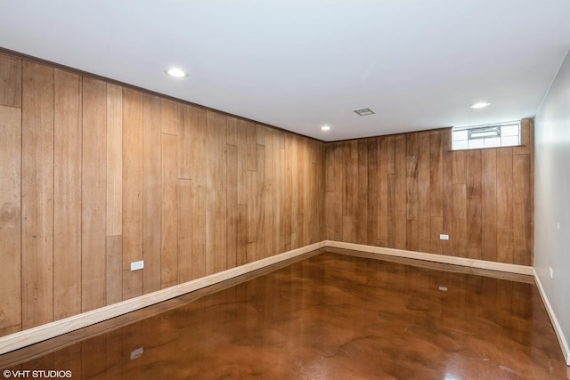 unfurnished room featuring concrete flooring, recessed lighting, baseboards, and wooden walls