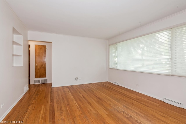 unfurnished room with ornamental molding, wood finished floors, baseboards, and built in features
