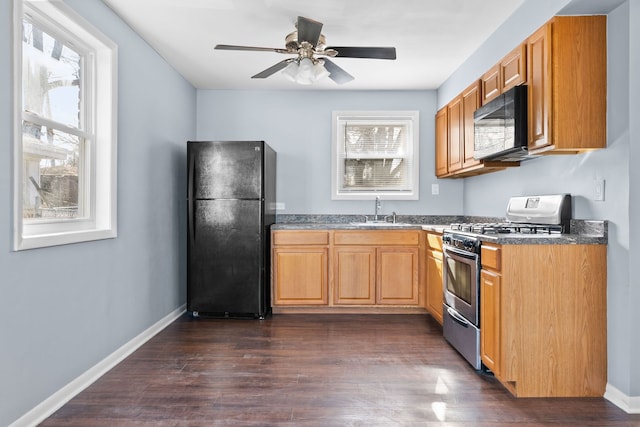kitchen with dark countertops, a sink, black appliances, ceiling fan, and dark wood-style floors