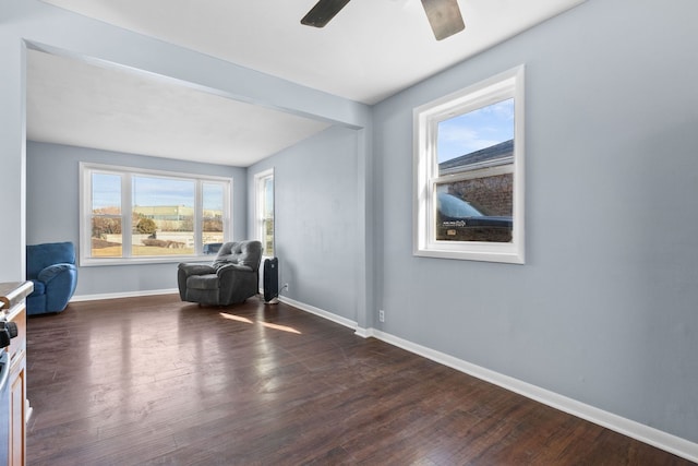 sitting room featuring dark wood finished floors, baseboards, and ceiling fan