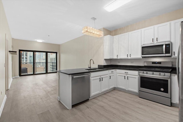 kitchen featuring dark countertops, appliances with stainless steel finishes, a sink, and light wood-style floors
