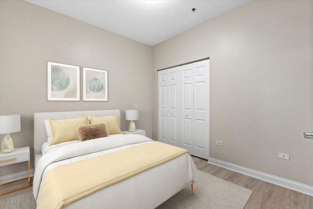 bedroom with baseboards, wood finished floors, and a closet