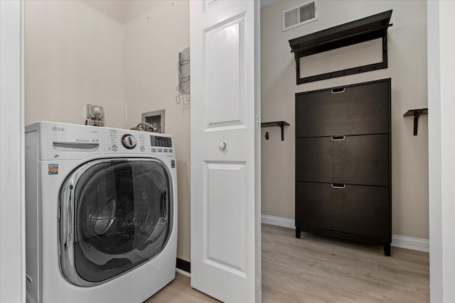 laundry area with laundry area, visible vents, light wood-style floors, baseboards, and washer / clothes dryer