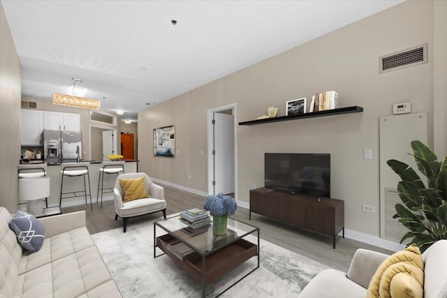 living area featuring light wood-type flooring, visible vents, and baseboards
