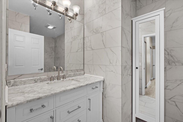 bathroom featuring marble finish floor, vanity, and tile walls