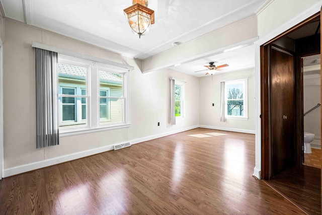 spare room featuring baseboards, ornamental molding, wood finished floors, and visible vents
