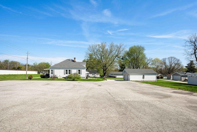 view of front facade with an outdoor structure, a front yard, and a detached garage