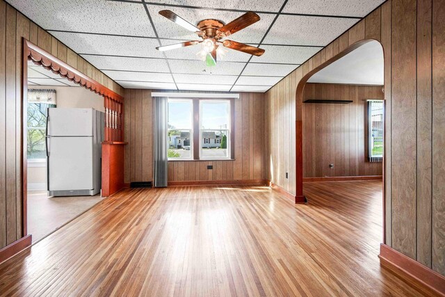 spare room featuring arched walkways, light wood finished floors, baseboards, and ceiling fan