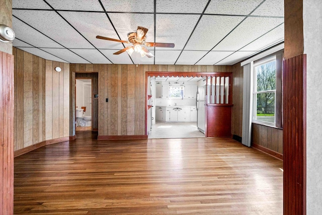 spare room featuring plenty of natural light, wooden walls, wood finished floors, and ceiling fan