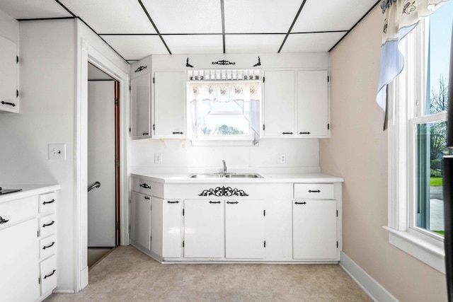 kitchen with plenty of natural light, a paneled ceiling, light countertops, and a sink