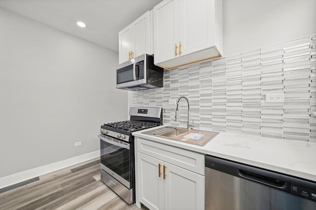 8045 S Escanaba Ave, Chicago, IL 60617 - kitchen featuring stainless steel appliances, light wood finished floors, backsplash, baseboards, and white cabinetry