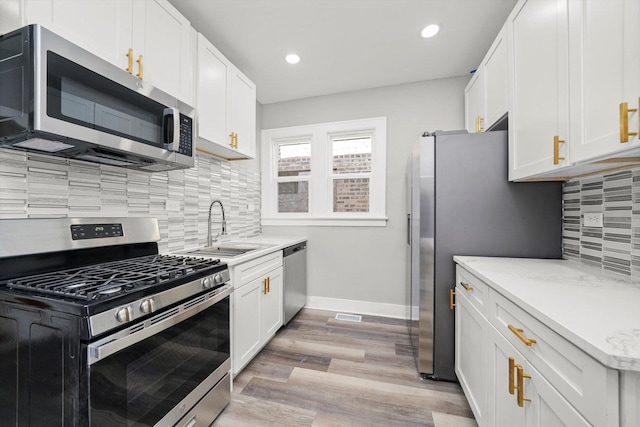 8045 S Escanaba Ave, Chicago, IL 60617 - kitchen featuring tasteful backsplash, a sink, light wood finished floors, white cabinets, and appliances with stainless steel finishes