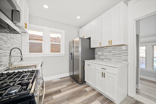 8045 S Escanaba Ave, Chicago, IL 60617 - kitchen with a sink, stainless steel appliances, light countertops, white cabinets, and baseboards