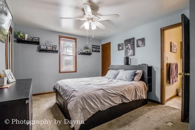 bedroom featuring light carpet, a ceiling fan, ensuite bathroom, and baseboards