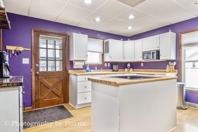 kitchen featuring white cabinets, light wood-style floors, and stainless steel microwave